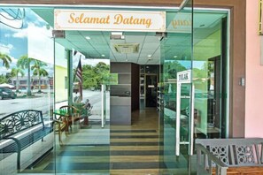 Zona de recepción con un cartel que dice "Selamat Datang" y un letrero "TOLAK" que indica una barra de comida.