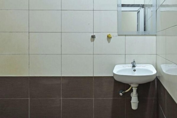 Un baño con un lavamanos blanco, un espejo y baldosas marrones.