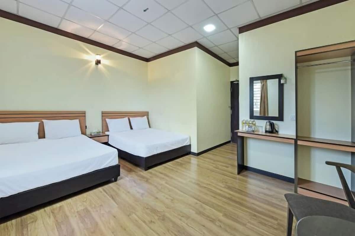 Una habitación de hotel con dos camas, un pequeño escritorio con espejo, una silla y una kitchenette.