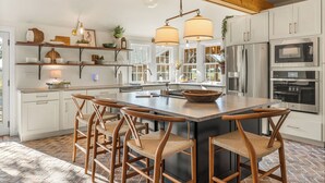 A modern kitchen with white cabinets, stainless steel appliances, and a large island with bar stools. - Completely renovated heritage home in the Ozarks Mountain region of SW Missouri. (Billings)