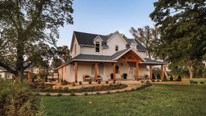 A two-story house with a covered porch, a landscaped front yard, and a large tree to the left. - Completely renovated heritage home in the Ozarks Mountain region of SW Missouri. (Billings)