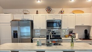 A modern kitchen with white cabinets, stainless steel appliances, and a central island with bar stools. - 3/2 Villa in most desired Richmond neighborhood in the Villages. Jan-Apr rental (The Villages)