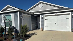 A two-story house with a garage, a driveway, and a bird sculpture in the front yard. - 3/2 Villa in most desired Richmond neighborhood in the Villages. Jan-Apr rental (The Villages)