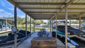 Une zone abritée avec une table et des chaises, des bateaux et une vue sur un lac.