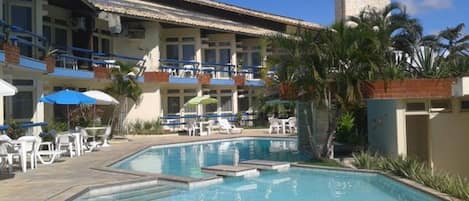 A hotel with a swimming pool, outdoor seating, and a sign for MEPs.