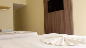 Quarto de hotel com duas camas, uma TV de tela plana na parede e design em painéis de madeira.
