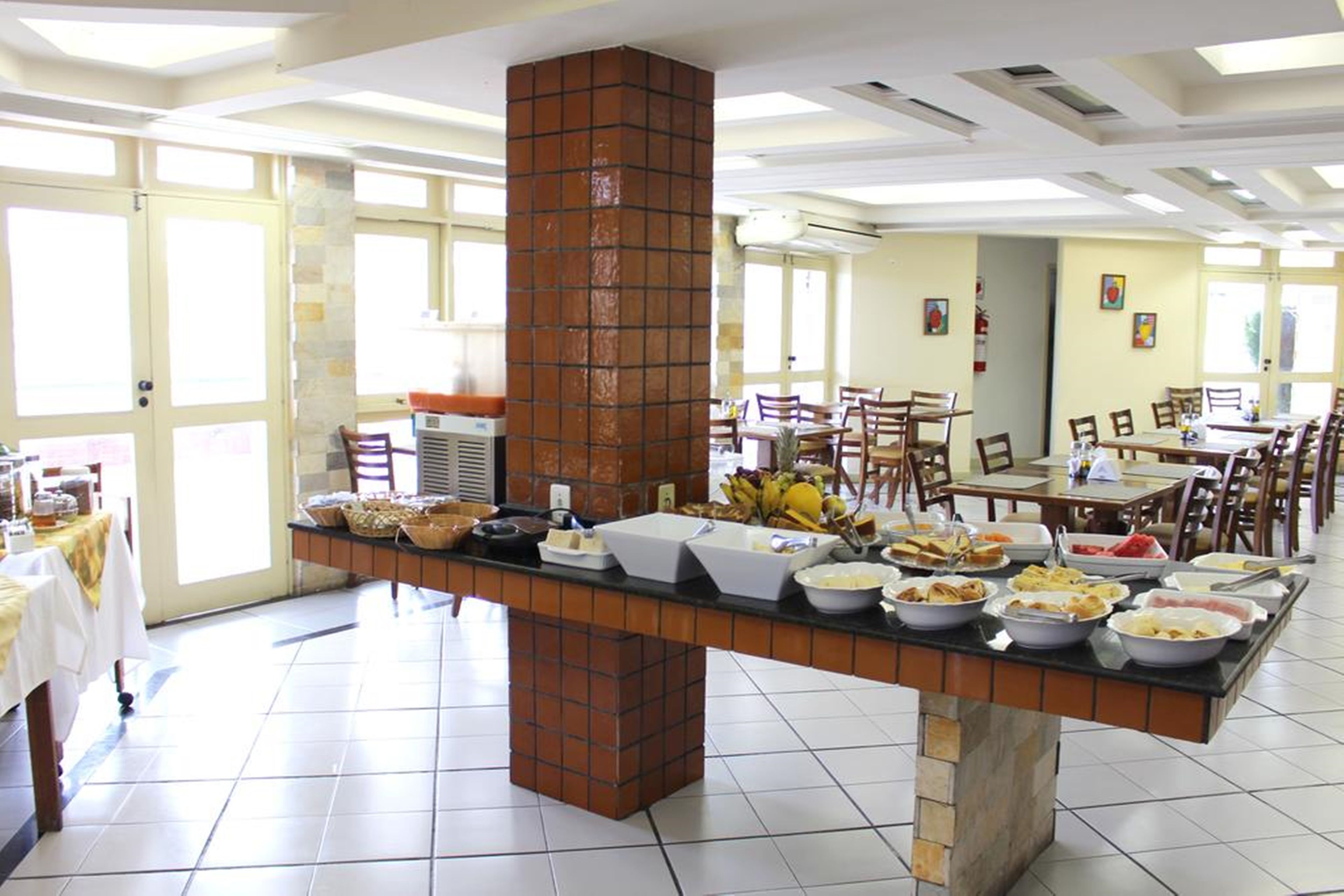 A buffet setup with various food items, a brick pillar, and a tiled floor.