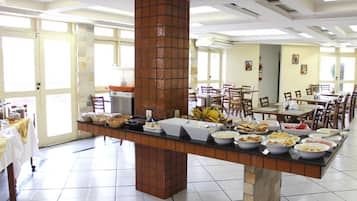 A buffet setup with various food items, a brick pillar, and a tiled floor.