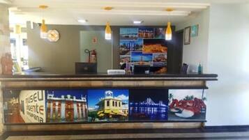 A reception desk with a laptop, a fire extinguisher, and a wall decorated with various photographs.