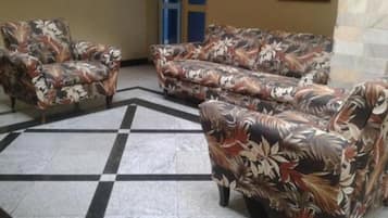 A lobby with a checkered floor, floral-patterned sofas, and a door in the background.