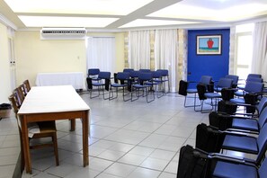A conference room with a long table, blue chairs, and a painting on the wall.