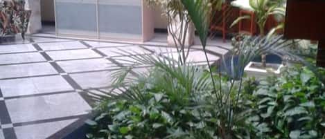 Un patio con suelo de baldosas, plantas en macetas y una zona de estar.