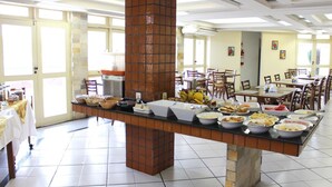 A buffet setup with various food items, a brick pillar, and a tiled floor. - Rede Andrade Aracaju (Aracaju)
