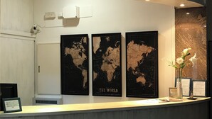 A reception desk with three world maps on the wall, a security camera, and a vase with flowers. - Hotel Cullera Coast by Mij (Cullera)