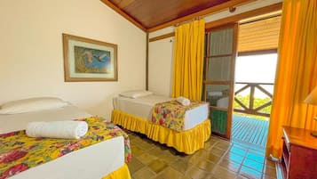 Um quarto com duas camas, um quadro na parede e uma janela com cortinas amarelas.