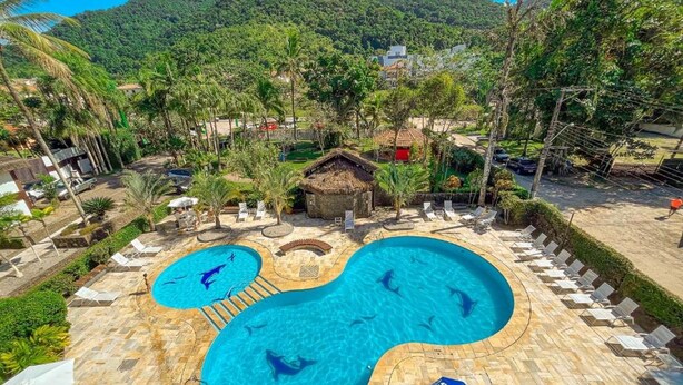 A pool area with two separate pools, lounge chairs, and a thatched-roof hut.
