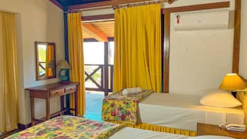 A hotel room with two beds, a desk, and a window with yellow curtains.