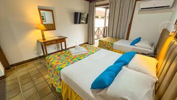 Quarto de hotel com duas camas, uma mesinha, uma televisão e um ar condicionado.