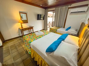 Habitación de hotel con dos camas, una mesita, un televisor y un equipo de aire acondicionado.