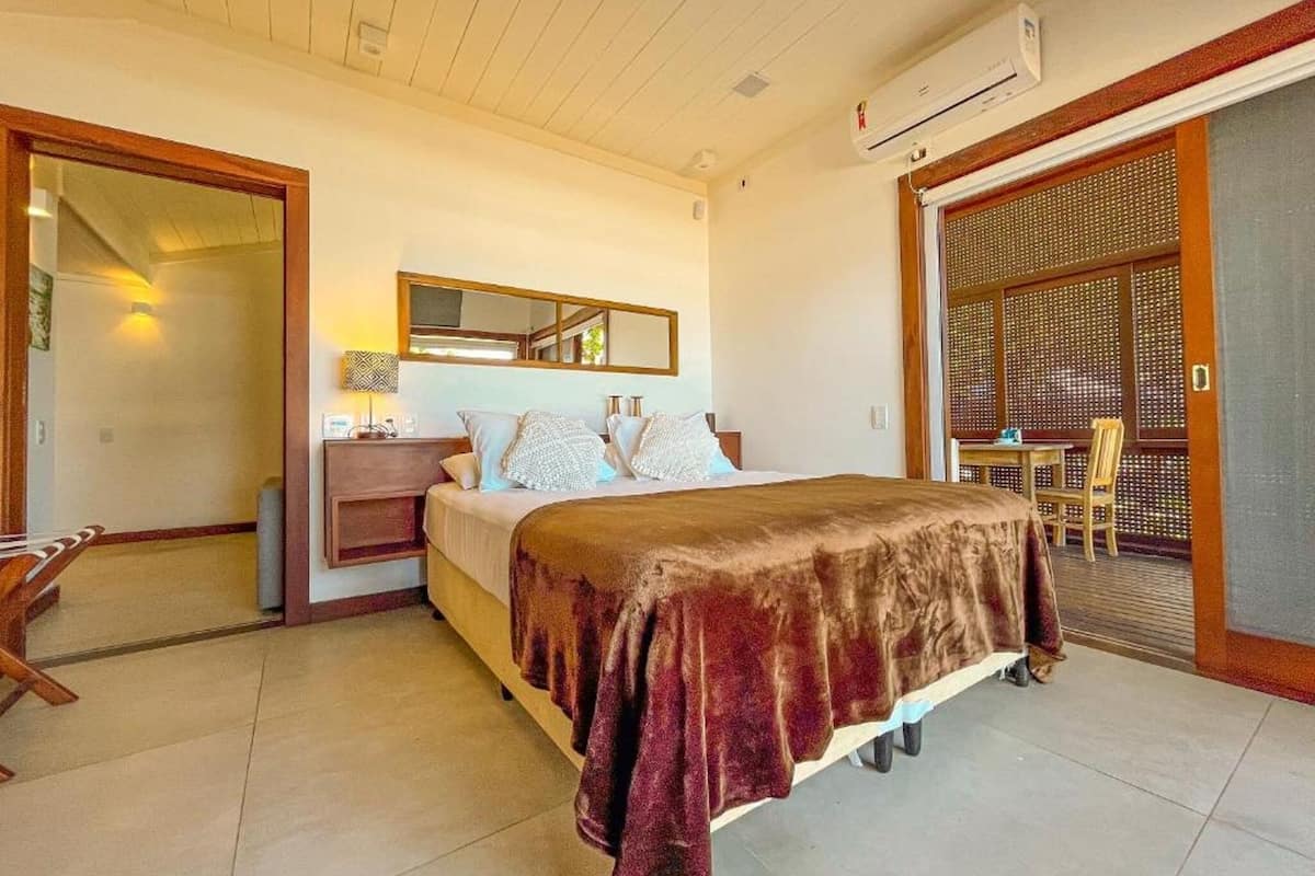 Une chambre d’hôtel comprenant un lit, une table de chevet, une lampe et une vue sur un espace de restauration accessible par une porte coulissante.