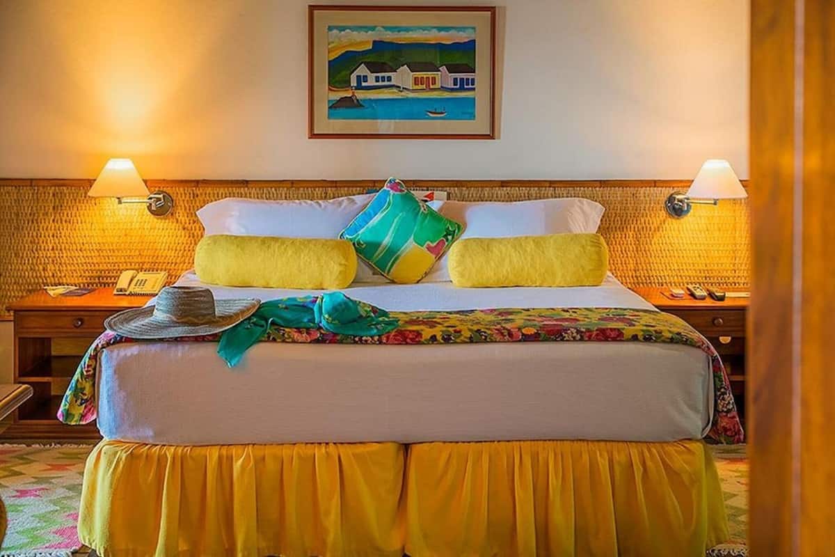 Une chambre d’hôtel avec un lit, deux lampes de chevet, un tableau au mur et un téléphone sur la table de chevet.