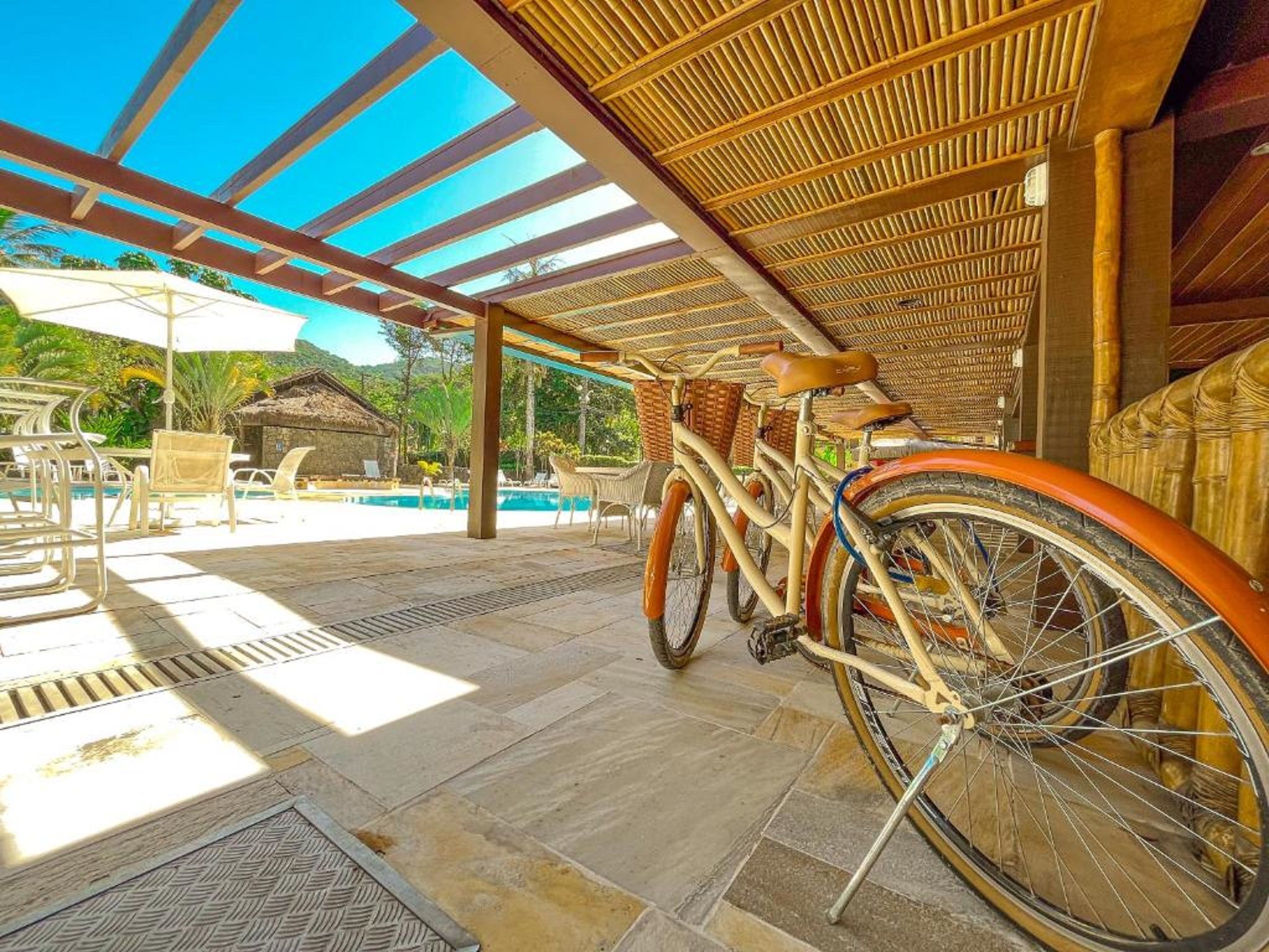 Uma área externa coberta com piscina, espreguiçadeiras e bicicletas.