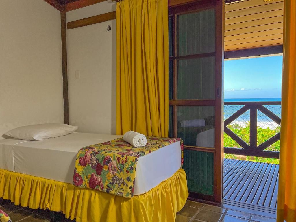 Una habitación con una cama, cortinas amarillas y vista al océano.
