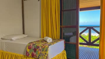 Una habitación con una cama, cortinas amarillas y vista al océano.