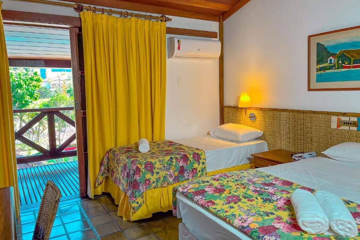 Une chambre avec deux lits, une fenêtre avec des rideaux jaunes, un plafond en bois et un tableau accroché au mur.
