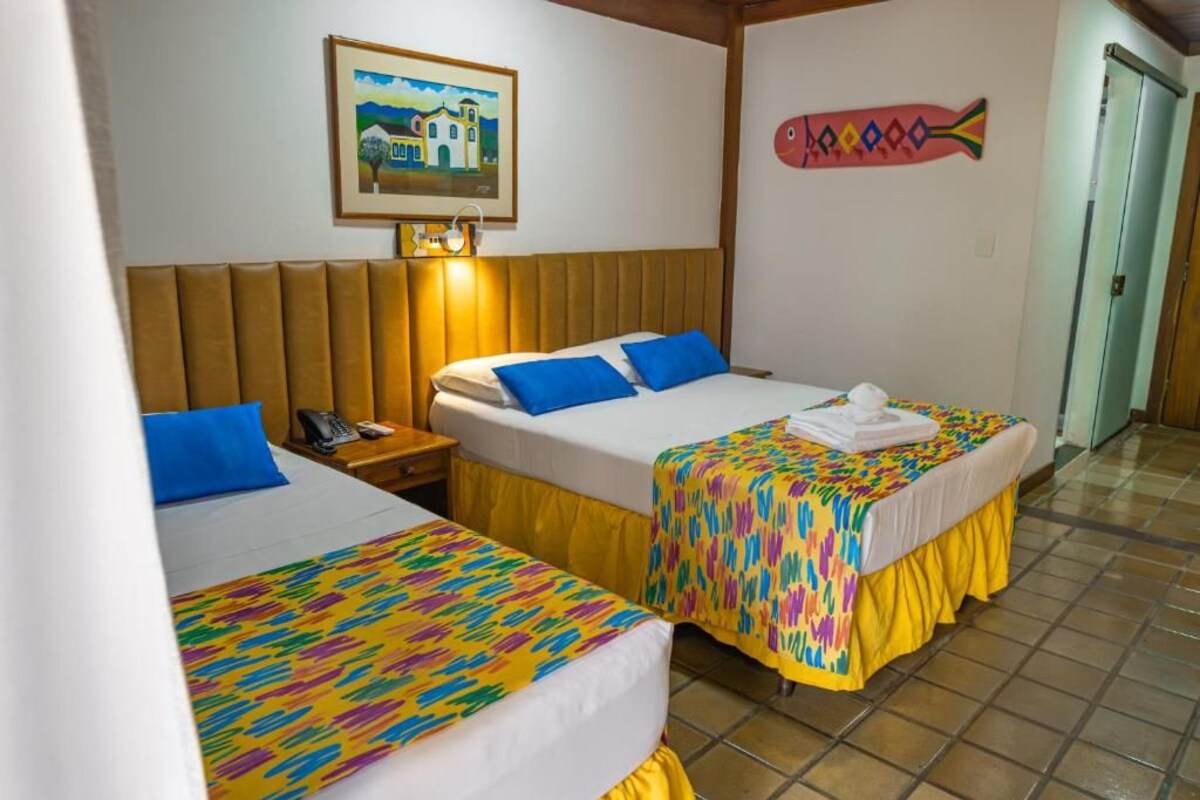 Una habitación de hotel con dos camas, una mesita de noche, un teléfono y un cuadro en la pared.