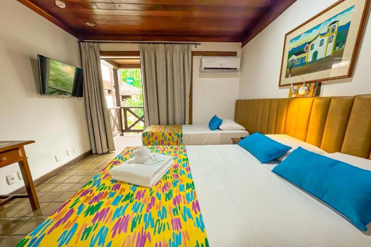 Habitación de hotel con dos camas, un televisor, un aire acondicionado y un cuadro en la pared.