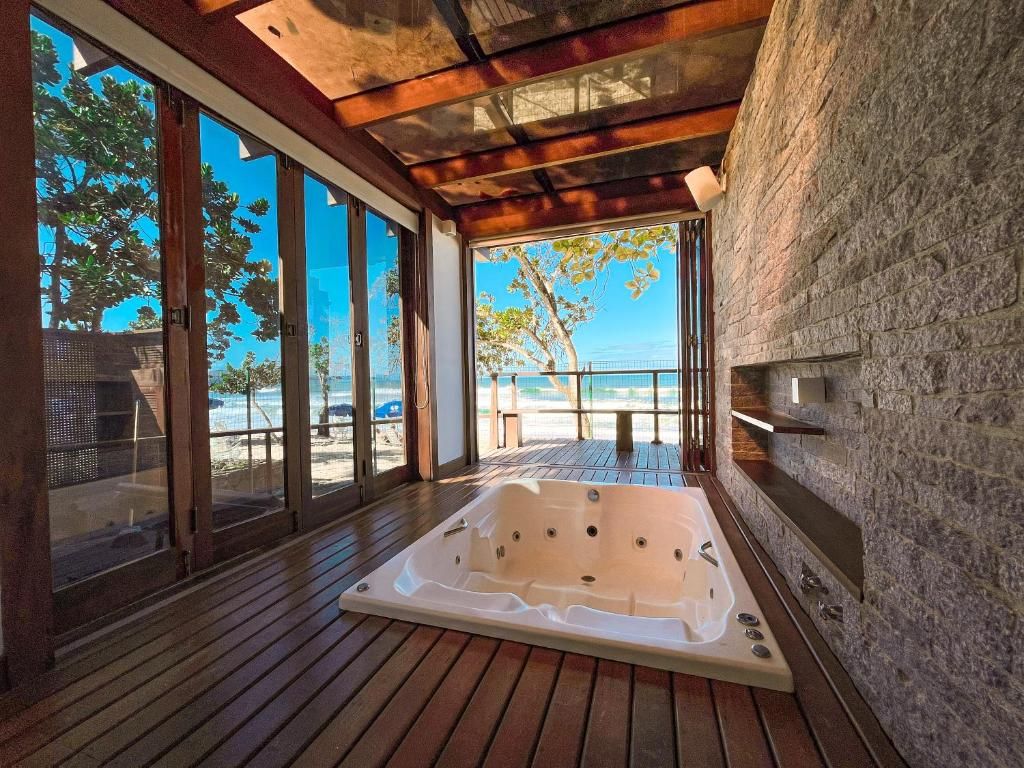 A spa area with a large hot tub, wooden deck, and a view of the beach.
