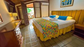 Un dormitorio con cama, mesita de noche, lámpara, ventana y puerta que da a un espacio exterior.