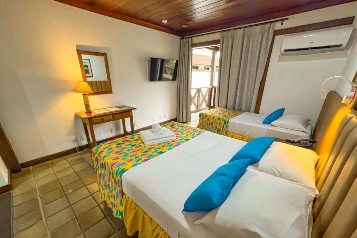 Habitación de hotel con dos camas, una mesita, un televisor y un equipo de aire acondicionado.