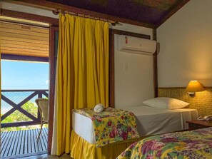Una habitación con cama, una silla y una ventana con cortinas amarillas.