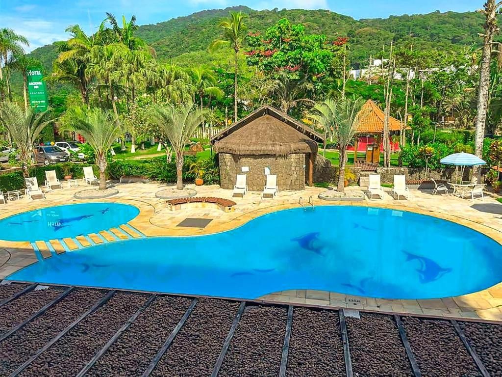 A hotel with two swimming pools, a thatched-roof hut, and a tropical garden.