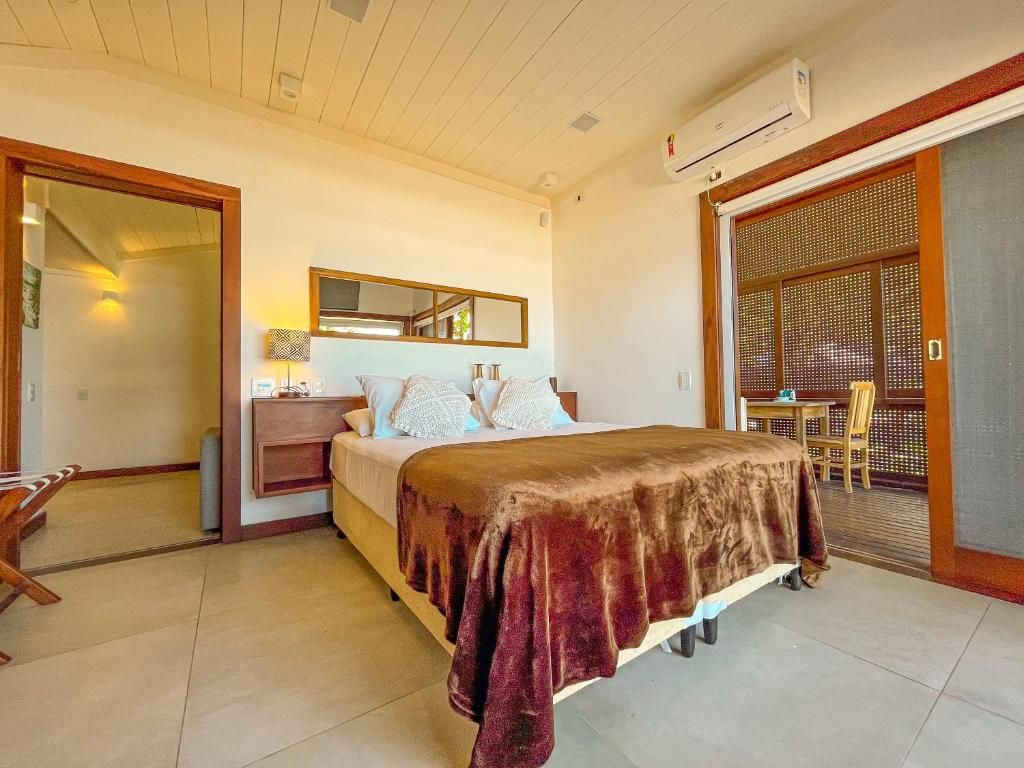 A hotel room with a bed, a nightstand, a mirror, and a sliding door leading to a balcony.