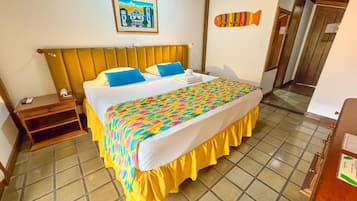 Habitación de hotel con cama, mesita de noche, una decoración de pez montada en la pared, un cuadro enmarcado y una puerta de madera.