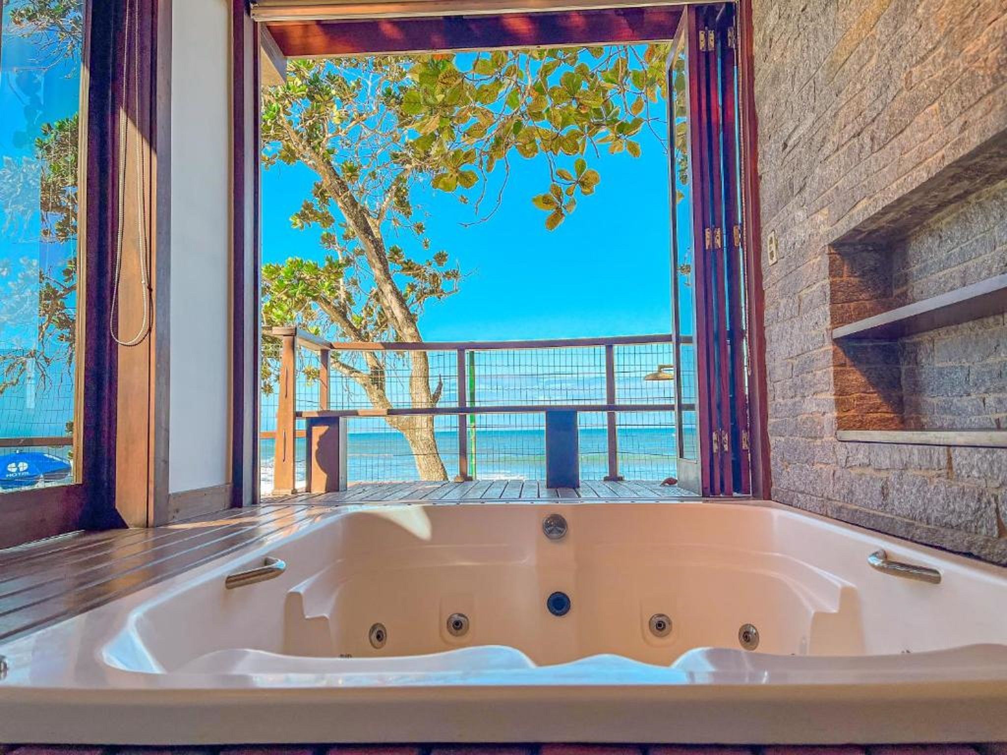 A hot tub with a view of the sea and trees.