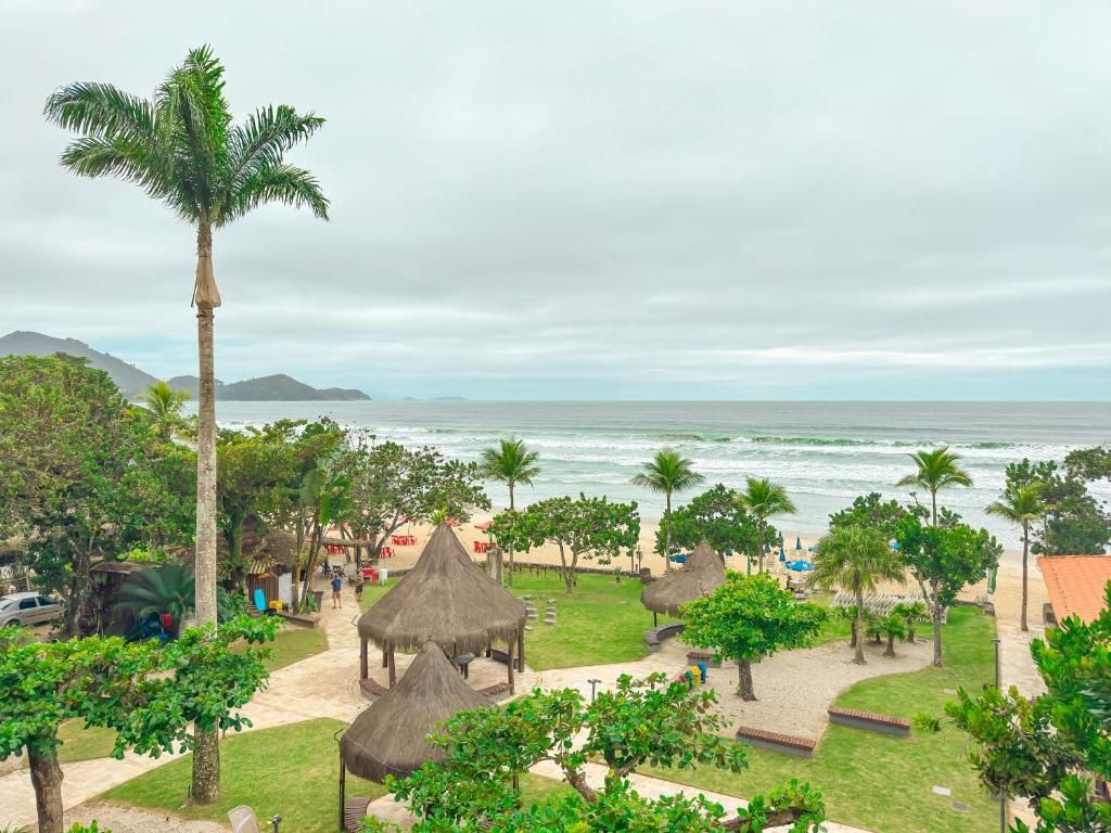 Um resort à beira-mar com estruturas de telhado de palha, palmeiras e vista para o oceano.