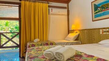 Una habitación con dos camas, una ventana con cortinas amarillas, un equipo de aire acondicionado y un cuadro en la pared.