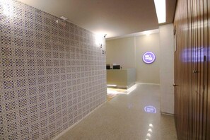 A hallway with patterned tiles, a reception desk, and a wooden door. - Samba Belo Horizonte Vintage Apart Hotel (Belo Horizonte)
