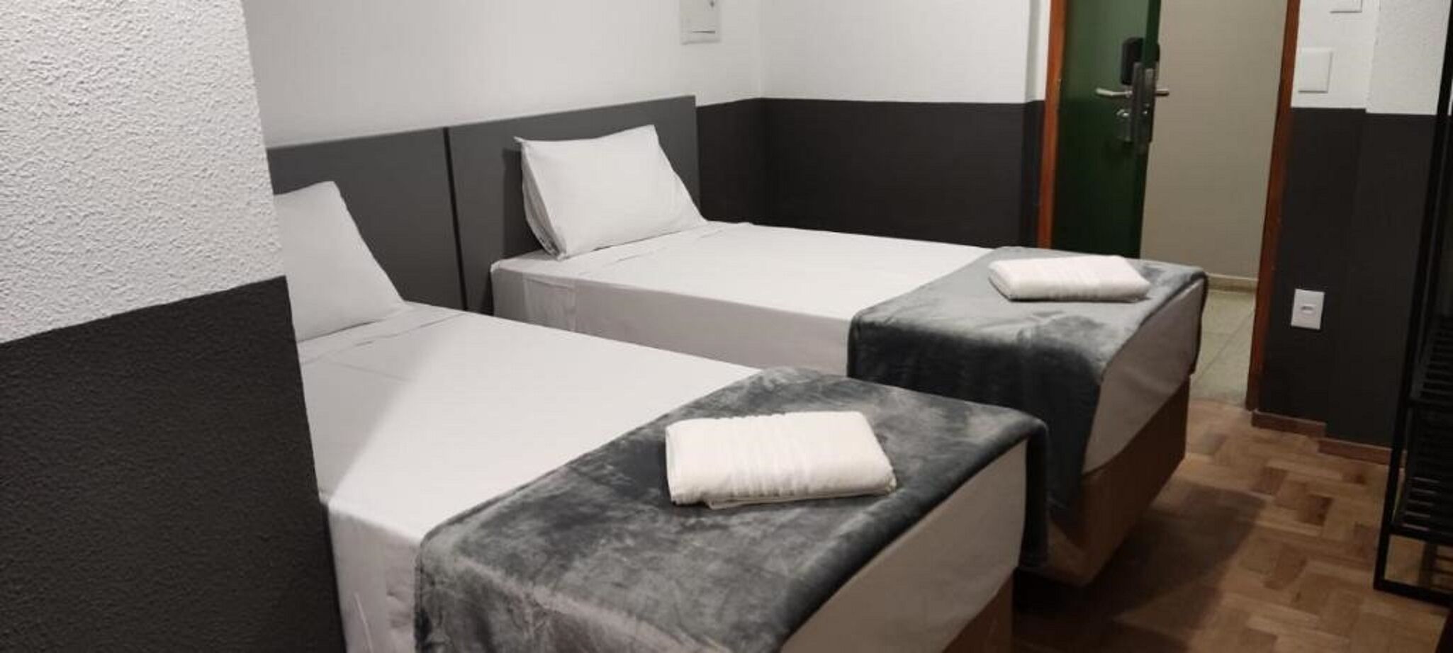 Una habitación con dos camas individuales, cada una con una almohada y una toalla doblada.