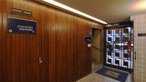 A hallway with a wooden wall, a sign indicating restricted access, and a door with a geometric glass design. - Samba Belo Horizonte Vintage Apart Hotel (Belo Horizonte)