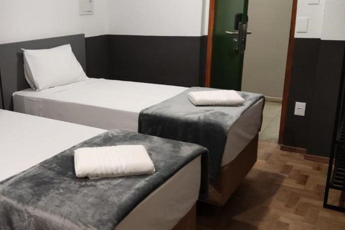 A room with two single beds, each with a pillow and a folded towel.