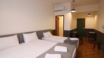 Quarto de hotel com duas camas, uma escrivaninha e uma cadeira.