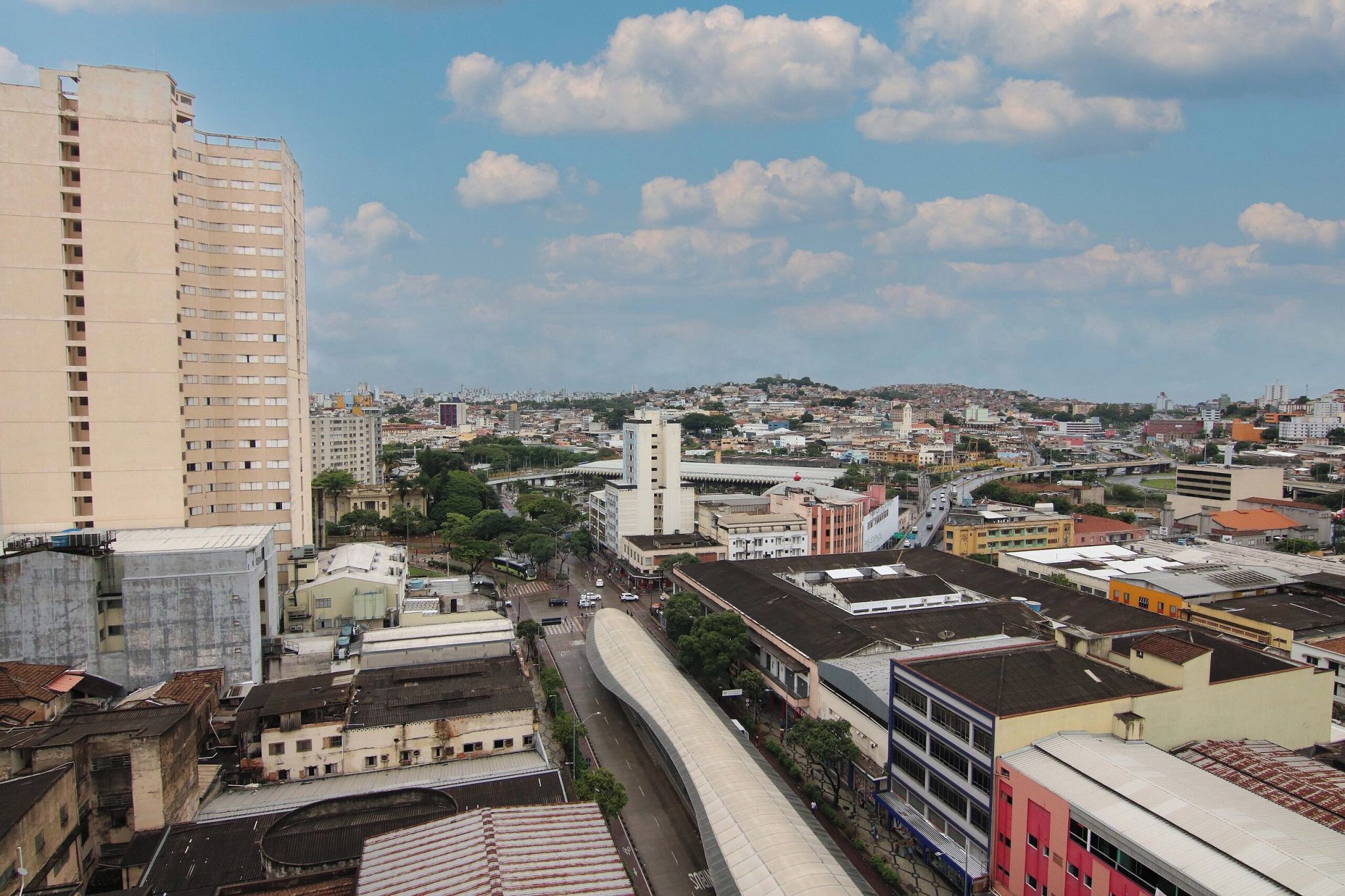 A cityscape with a prominent high-rise building, a curved bridge, and a mix of residential and commercial buildings.