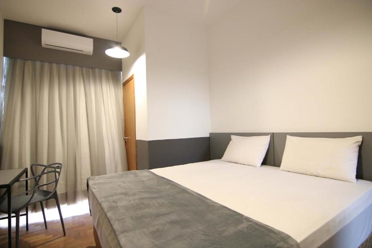 Hotellihuone, jossa on sänky, työpöytä ja tuoli.
