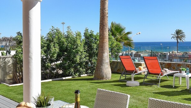 Ein Essbereich im Freien mit einem Tisch für zwei Personen, der einen schönen Blick auf das Meer und Palmen bietet.
