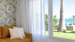 Ein Zimmer mit einer Couch, einem Tisch mit Zitronen und Blick auf das Meer und Palmen.